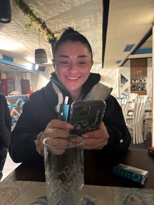 Woman photographed with phone and device in indoor setting