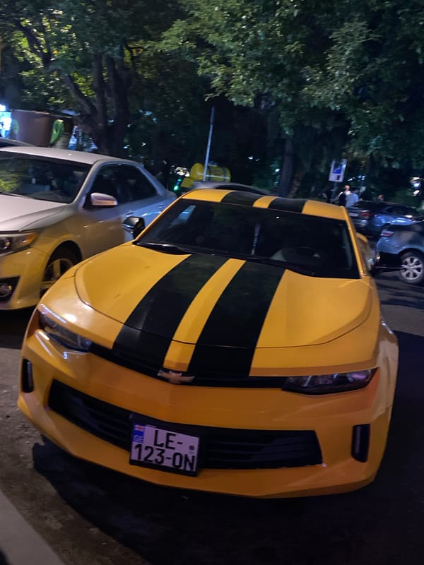 Bumblebee-styled Camaro parked on a Batumi street at night