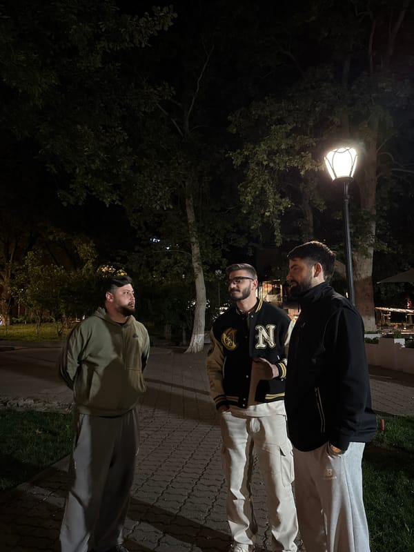 Three men gather on illuminated walkway in Yerevan park