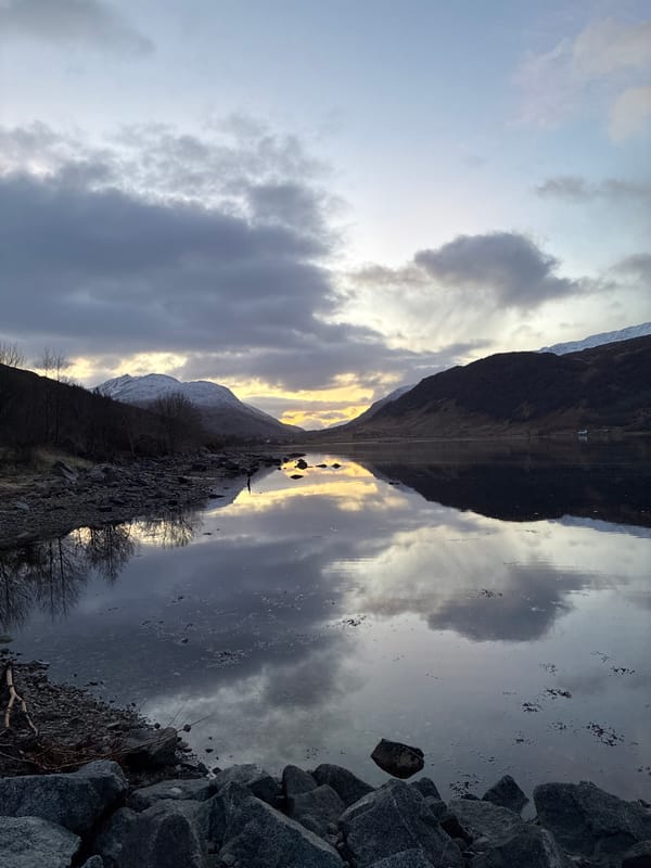 Mirror-like water reflections captured under stormy skies in Strontian