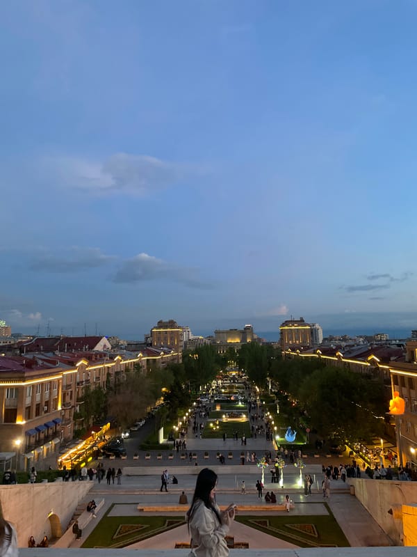 Evening strollers gather at illuminated Yerevan Cascade at dusk