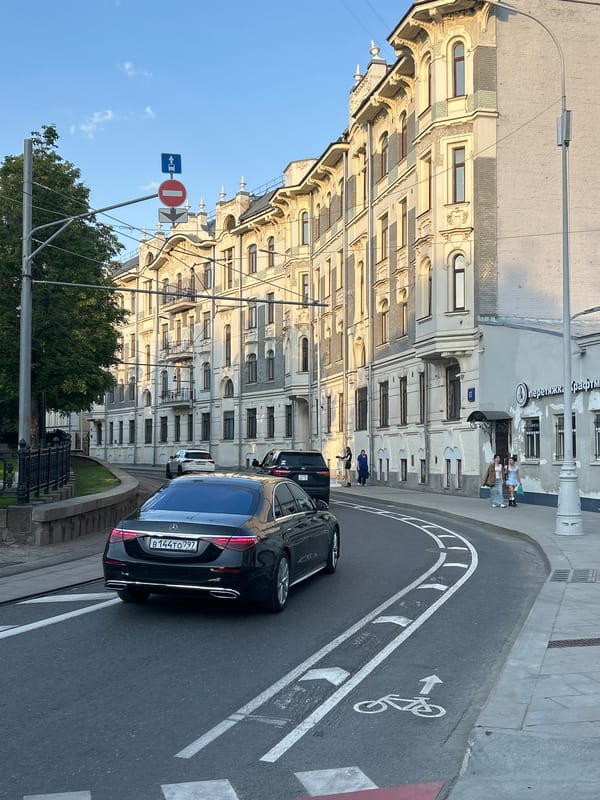 Street scene captured: Mercedes sedan, woman with straw bag