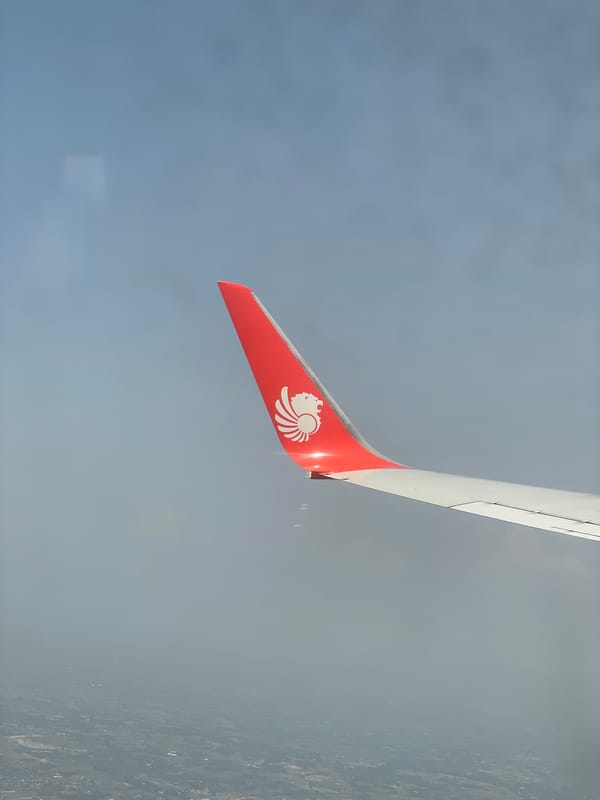 Aircraft wing photographed from airplane window over Bangkok