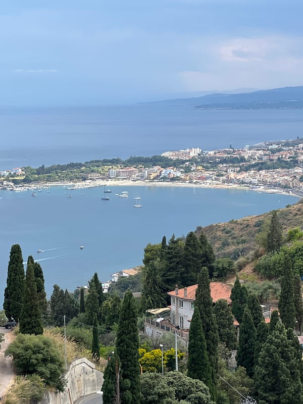 Overcast views of Taormina's bay from above the treeline