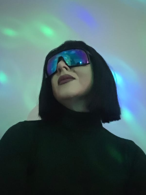 Woman in reflective sunglasses photographed in colorful club lighting