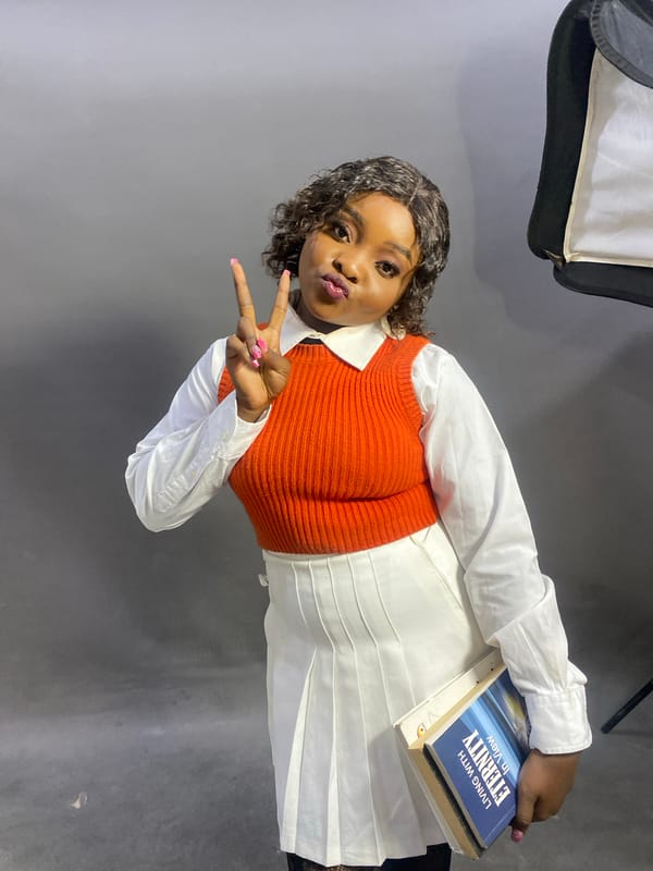 Student poses with books during studio photo session in Jos