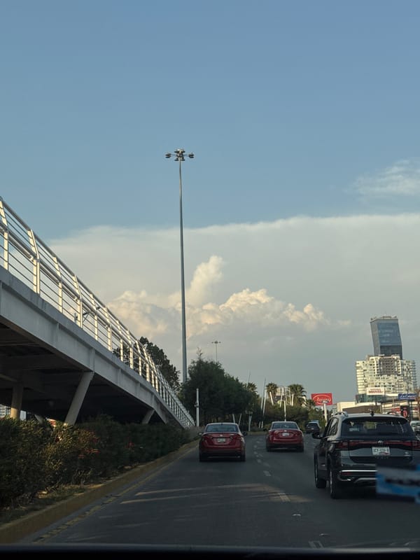 Traffic flows through Puebla streets near Coca-Cola billboard