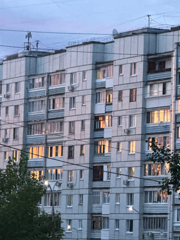 Friends hanging roadside at golden hour near apartment building
