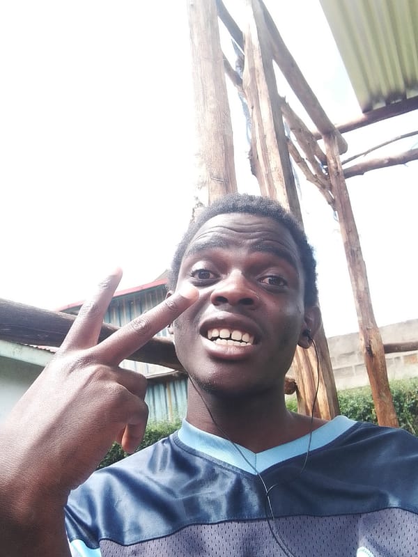 Man makes peace sign gesture outdoors near wooden structure