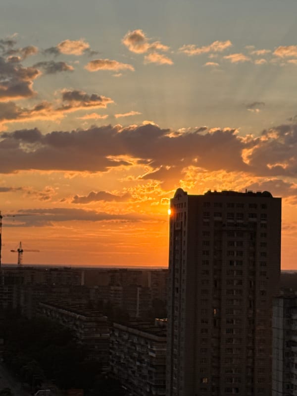 Rainbow and golden light over a dense city skyline at sunset