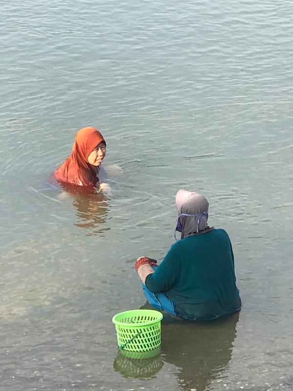 Two women enjoy early morning water activity in Lhokseumawe