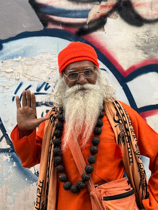 Orange-robed figure by a graffiti wall in Pushkar