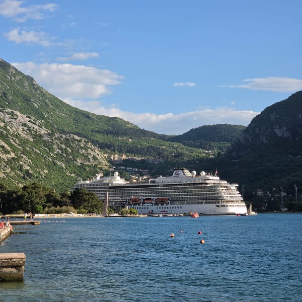 Cruise ship docks in Dobrota as tourists stroll waterfront