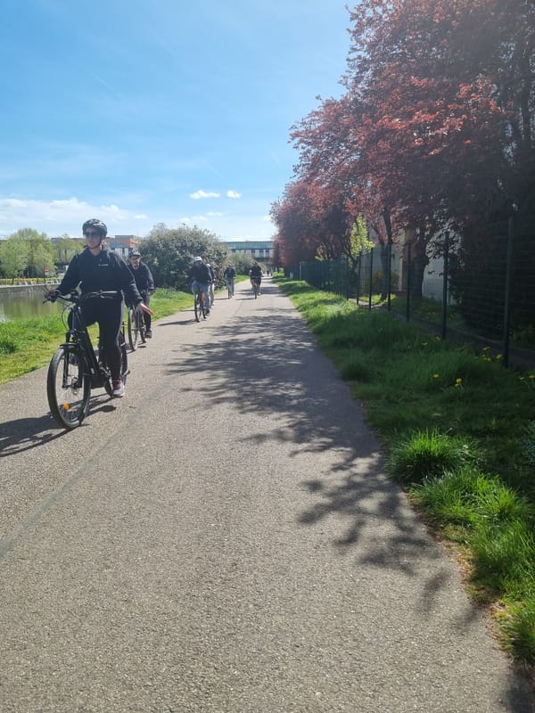 Cyclists ride canal path in Nancy amid autumn scenery