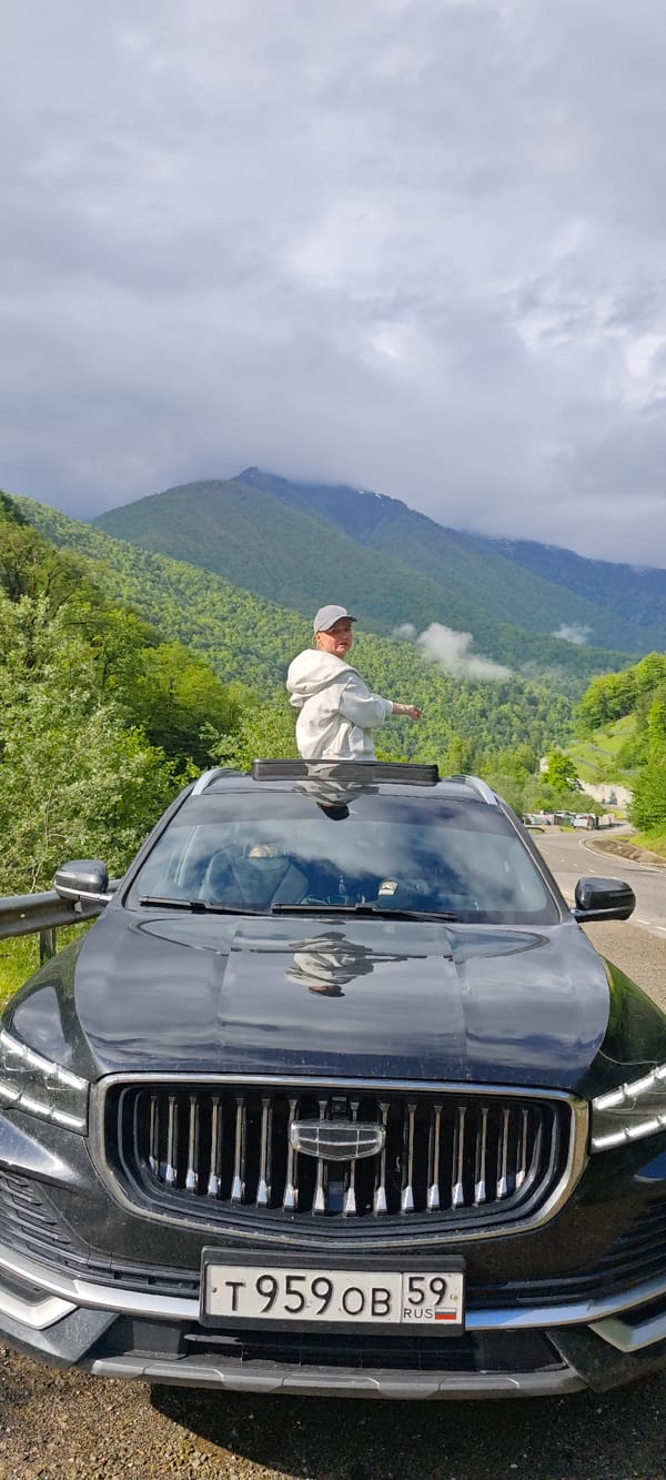 Person stands through sunroof taking photos from roadside car