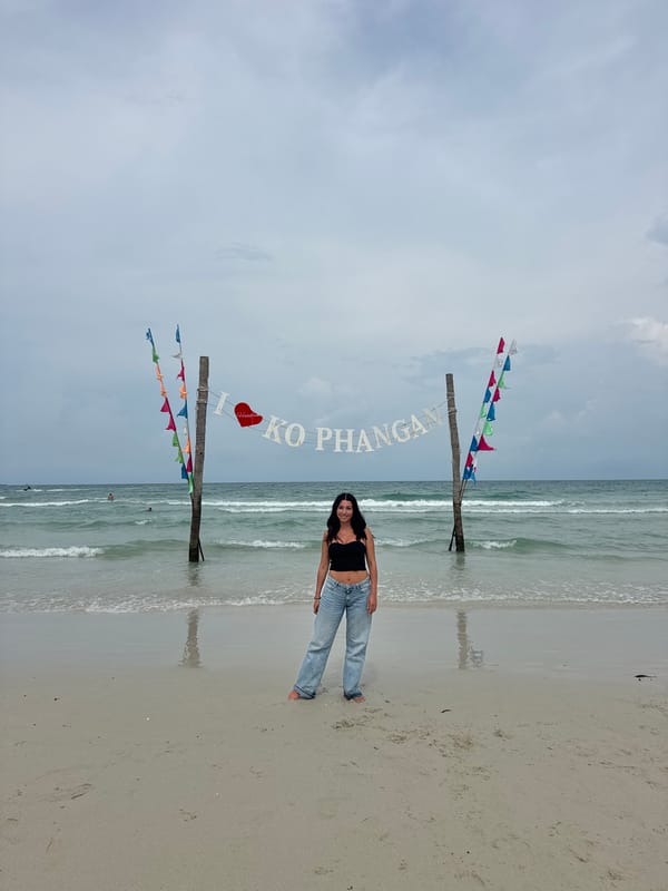 Tourist visits Ko Phangan beach, poses by landmark sign