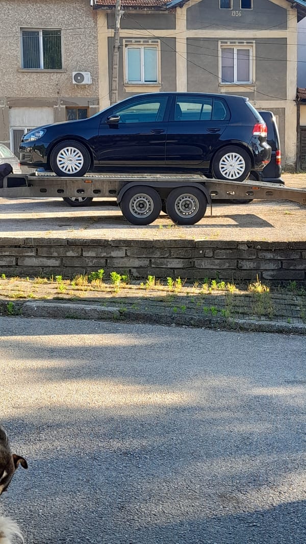 Blue Volkswagen Golf spotted on car transporter near stone wall