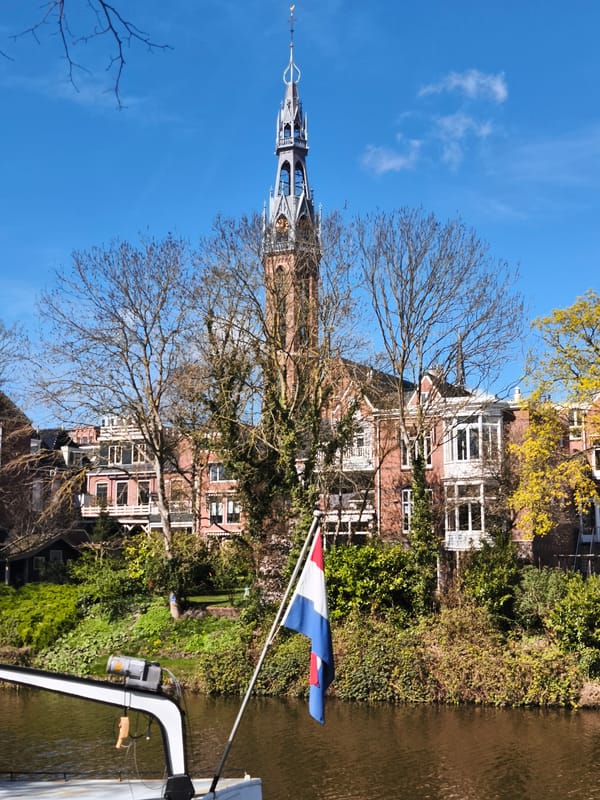 Boats moored along blooming Groningen canals near historic clock tower