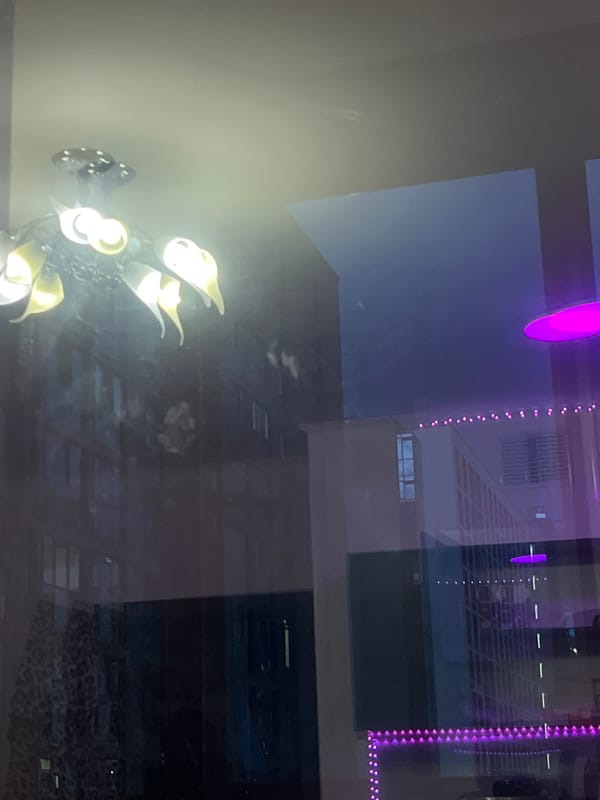 Glass reflection captures modern chandelier and mixed interior elements