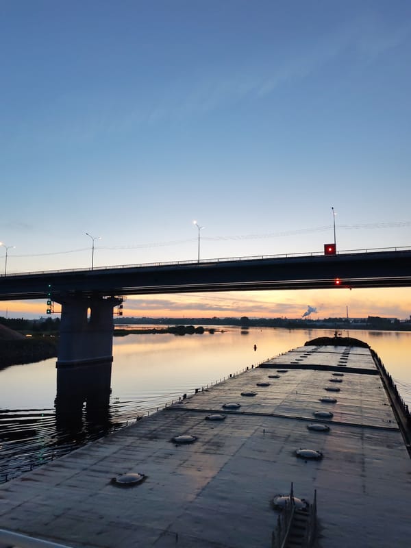 Barge passes under bridge at sunset on Sheksna River