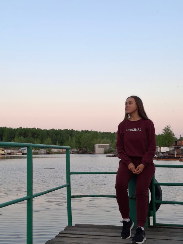 Woman sits on deck railing overlooking water in Chaikovsky