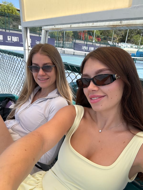 Two women sit by tennis court in Tel Aviv