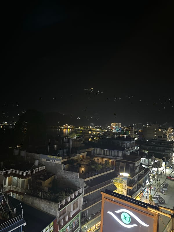 Night panorama captures illuminated Pokhara lakeside cityscape from elevation