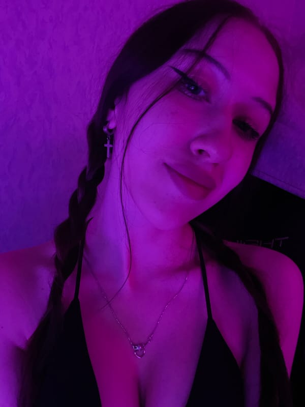 Woman documents evening selfie session in purple-lit bedroom in Votkinsk
