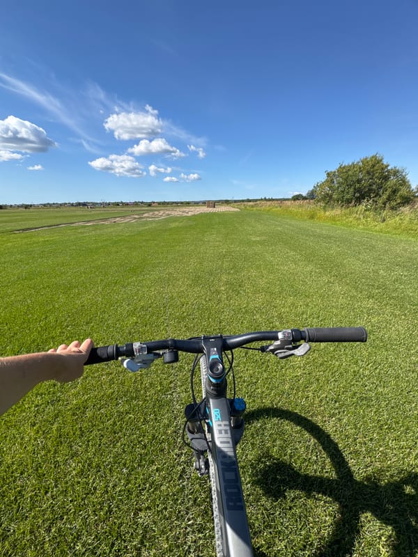 Sunny afternoon bike ride across a green field in Kempelevo