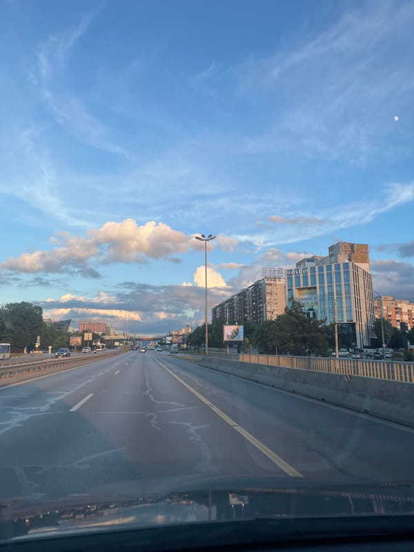 Urban drive past glass towers under a dramatic afternoon sky
