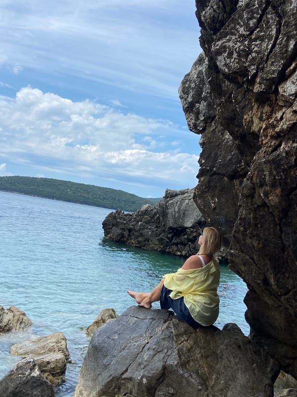 Woman sits on coastal rocks overlooking Adriatic in Montenegro