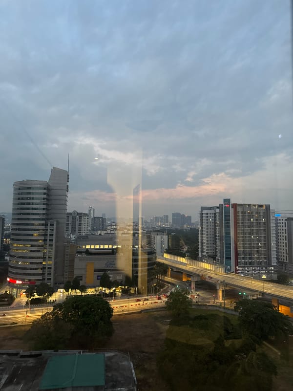 Kuala Lumpur skyline at dusk through a high-rise window