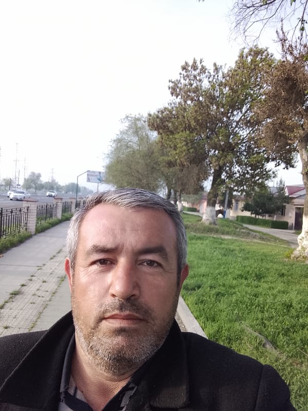 Man takes selfie on tree-lined sidewalk in Uzbekistan