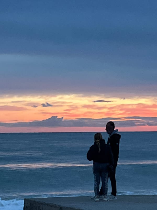 Adult and child watch sunset on Alanya beach