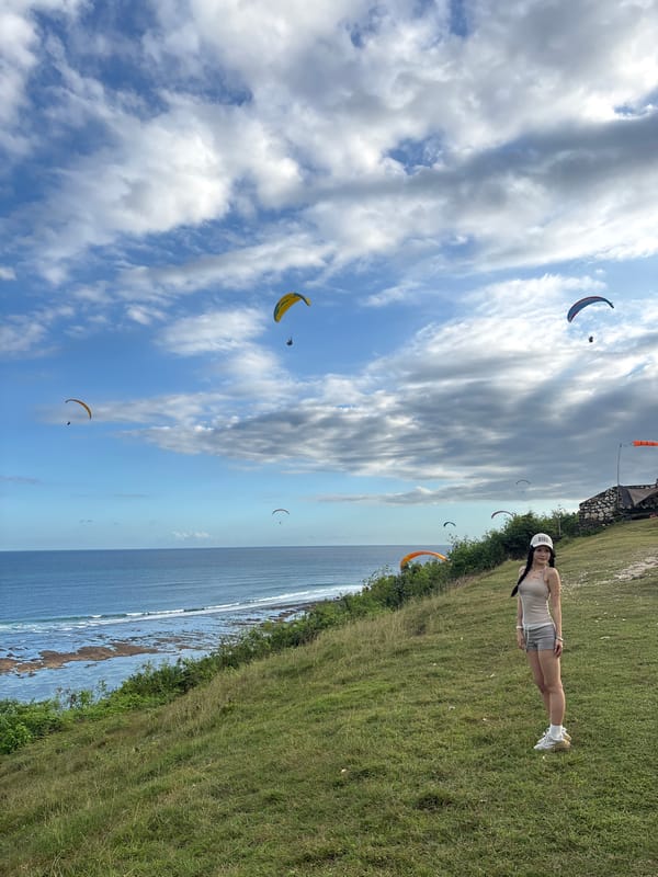 Paragliders soar over Kuta Selatan cliffs as tourists watch