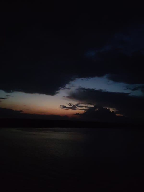 Dark twilight clouds captured over water with sunset glow