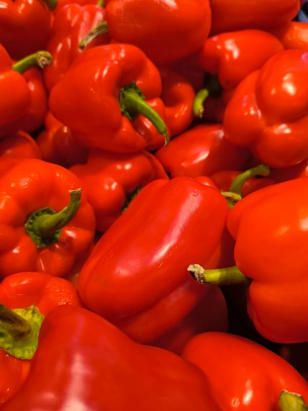Pile of glossy red bell peppers shot up close