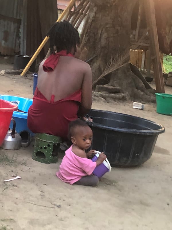 Woman conducts household activities with child in Atani, Nigeria