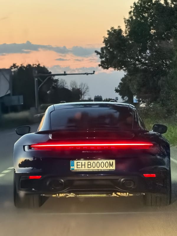Dark blue Porsche rolling through rural Bulgaria, brake lights on