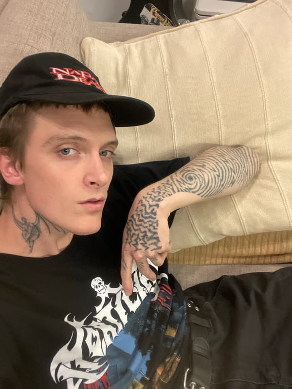 Person with tattoos rests on couch in Vicente López