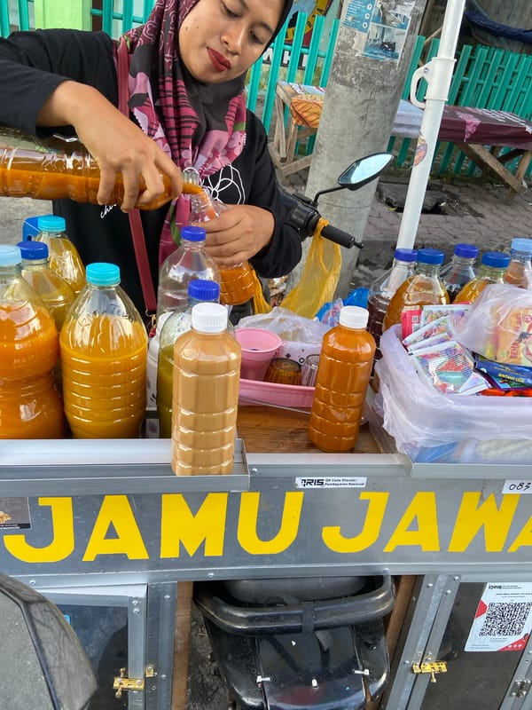 Beverage vendor serves customers from cart in Sumbersari