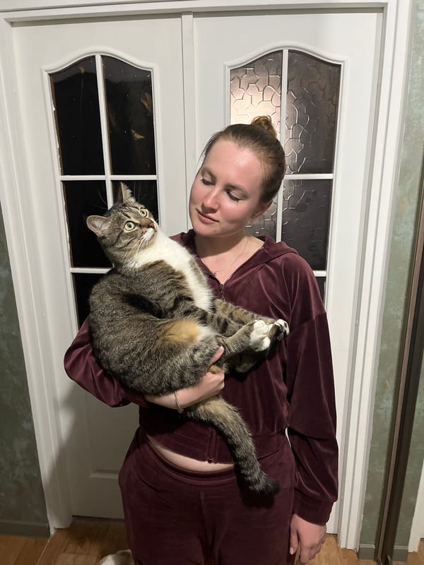 Woman holds tabby cat outside white door in Hrodna
