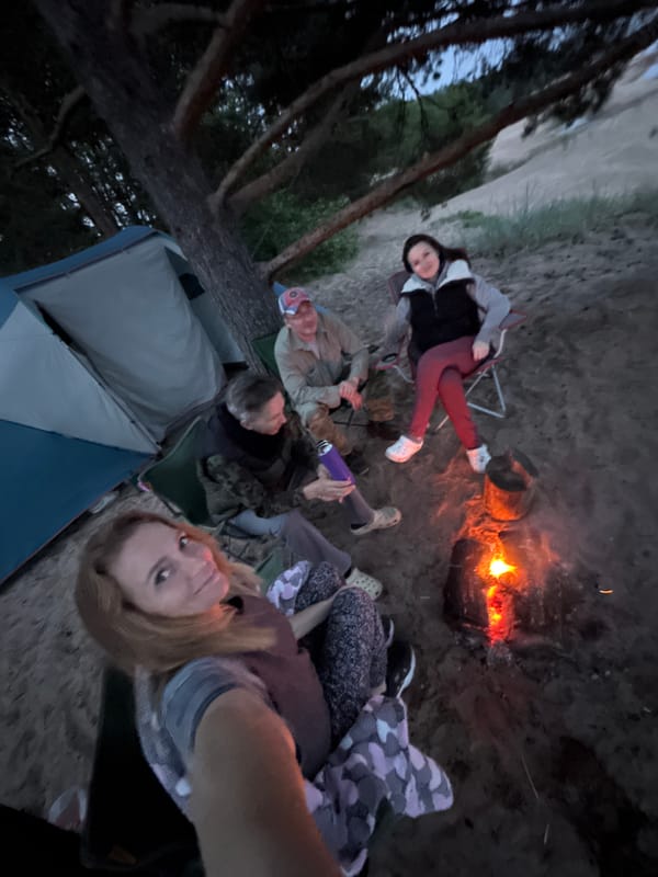 Four adults gather around campfire in Russia at dusk
