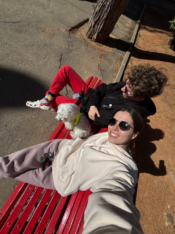 Two people, dog rest on park bench in Bat Yam