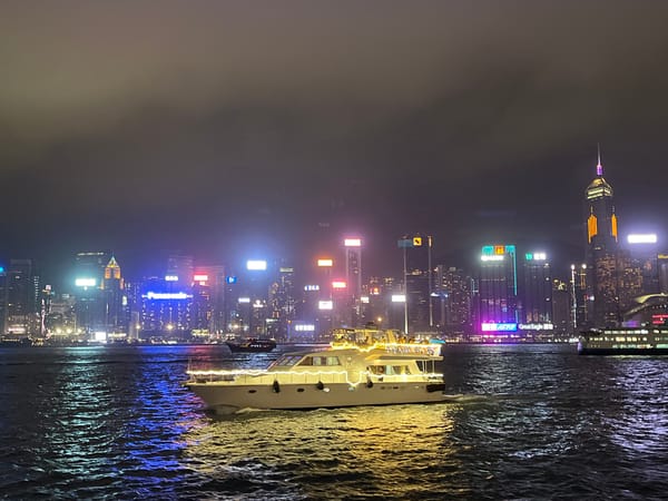 Yacht sails through illuminated Victoria Harbour, Hong Kong