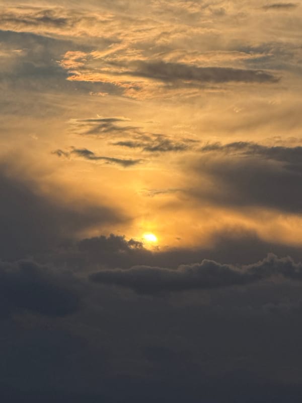 Golden sunset breaks through heavy clouds over a city
