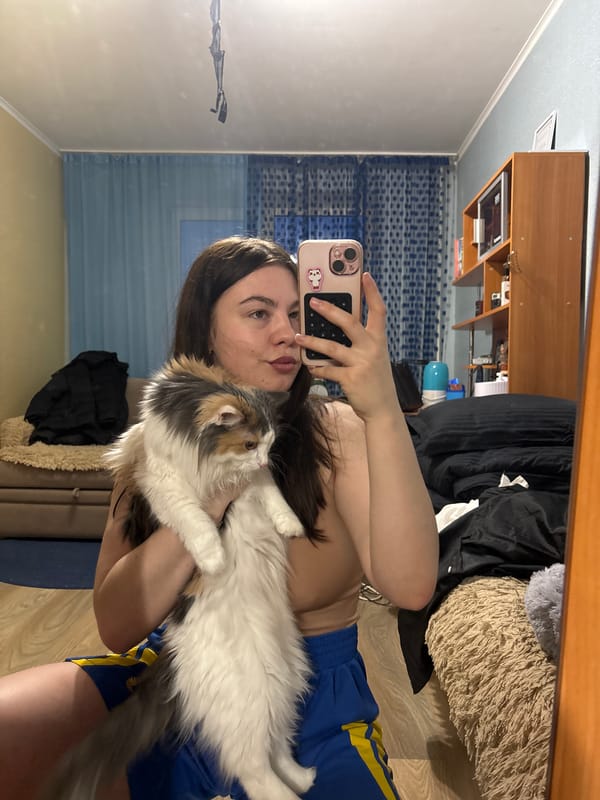 Woman takes mirror selfie with cat in Perm bedroom