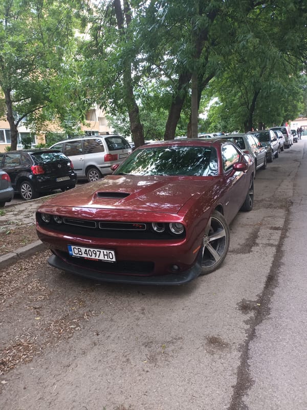 Woman reclines on Dodge Challenger hood in city street