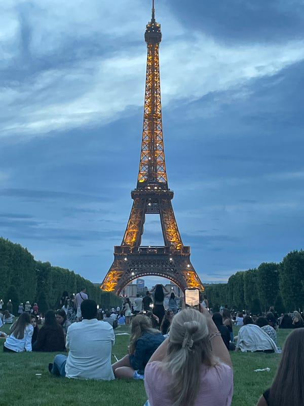 Evening crowd gathers at illuminated Eiffel Tower in Paris