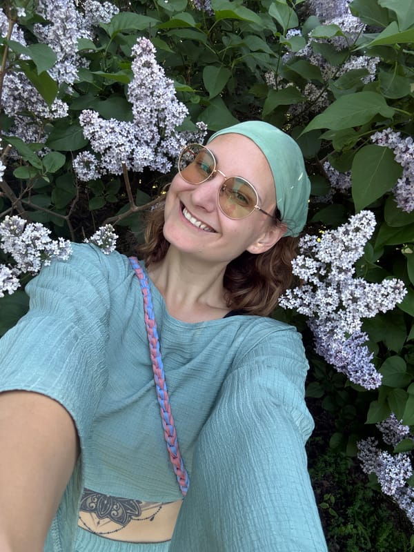Woman poses for selfie among blooming lilacs in spring